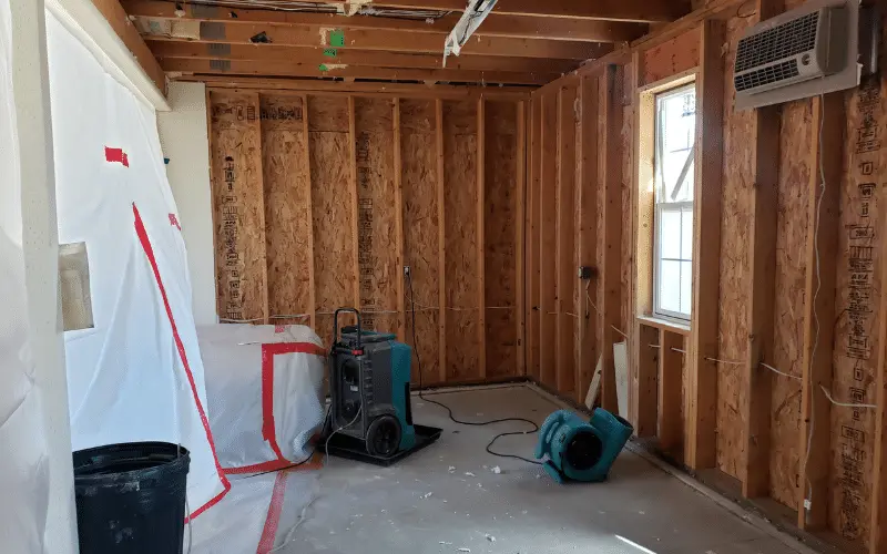 A room with wooden walls and a window going through water damage restoration