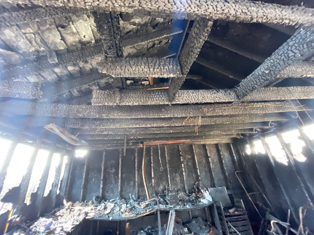 Charred roof framing inside the burned shed